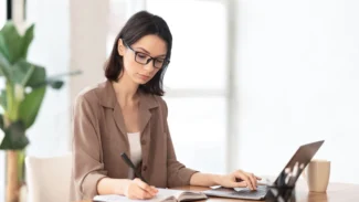 ragazza che prende appunti con un quaderno e un portatile