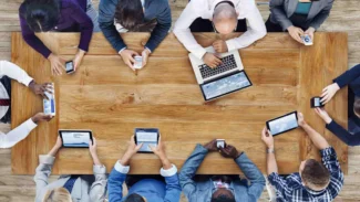 persone intorno ad un tavolo con dispositivi informatici