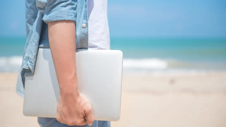 ragazzo che regge il portatile vicino al mare